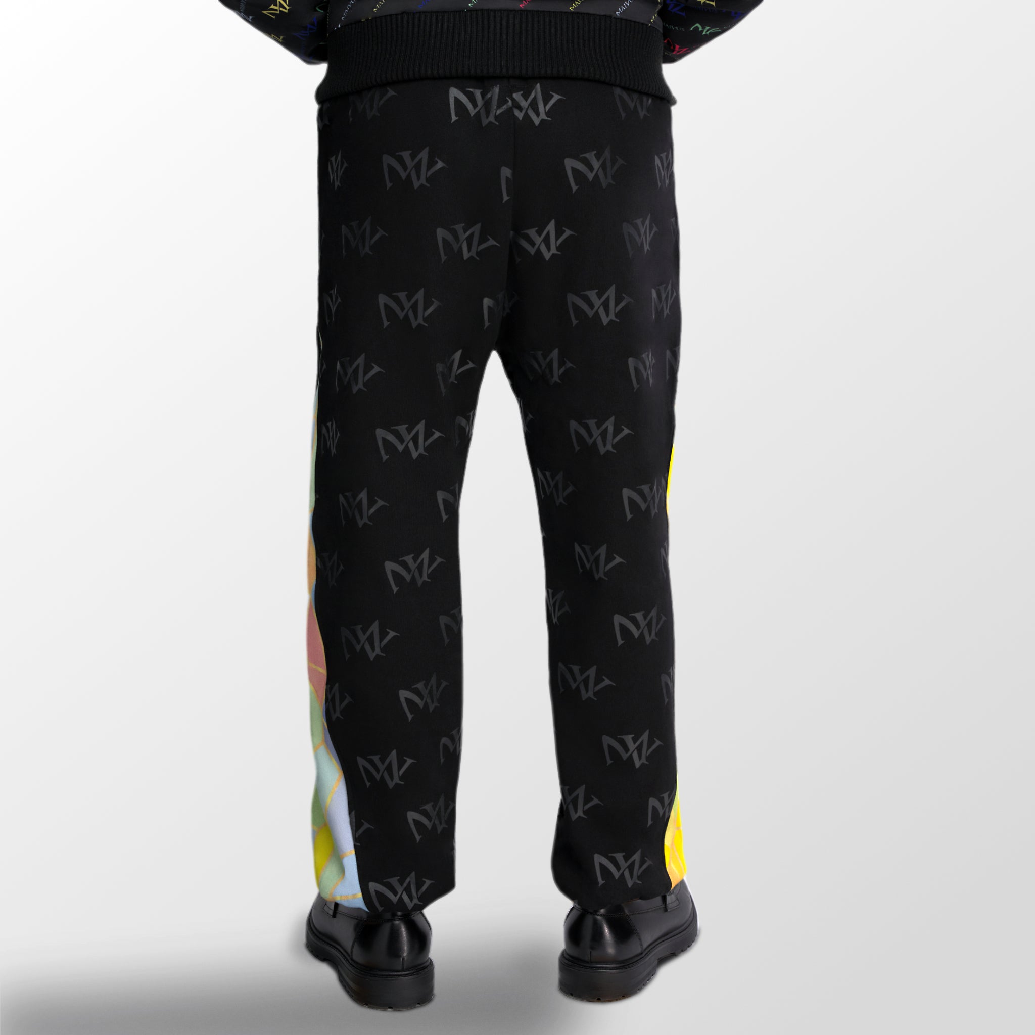 Model wearing the luxury multicolored joggers with 'MV' branding and geometric shapes from 'MAIVUS' against a white studio backdrop
