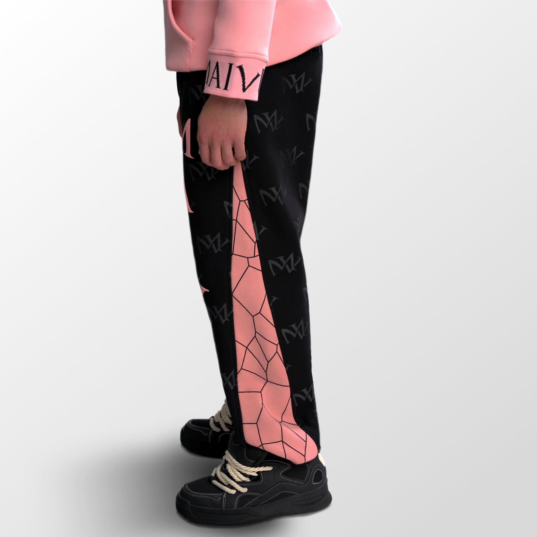 Model wearing the luxury black and pink joggers with 'MV' branding and geometric shapes from 'MAIVUS' against a white studio backdrop