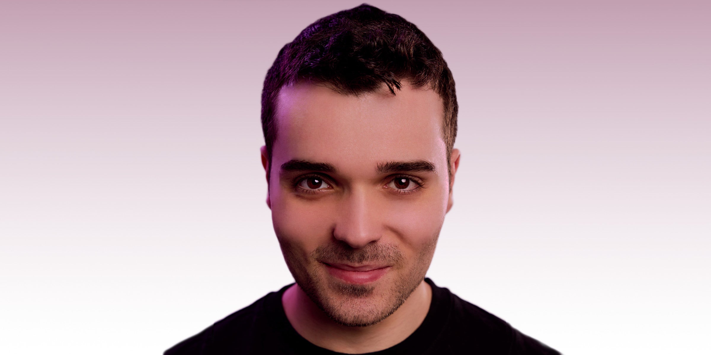 A man named Cameron Ocasio with short dark hair and a black shirt against a light purple background