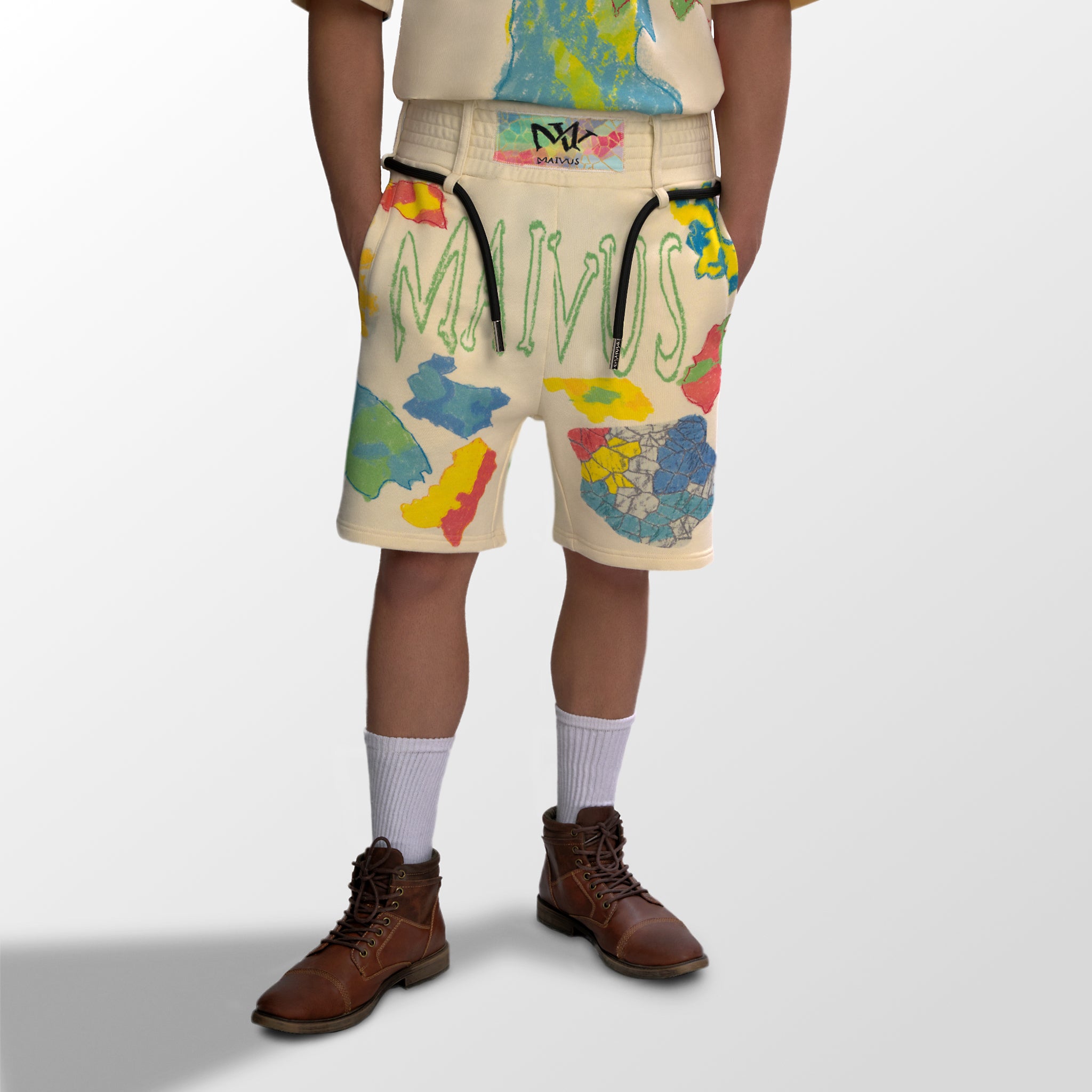 Model wearing the luxury multicolored shorts with abstract shapes and 'MAIVUS' branding from 'MAIVUS' against a white studio backdrop