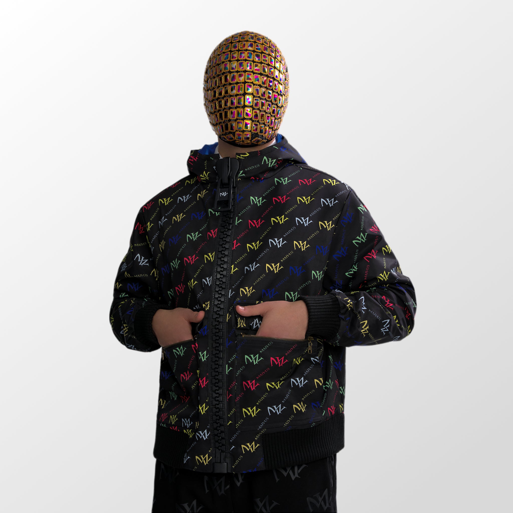 Model wearing the luxury multicolored jacket with 'MV' branding from 'MAIVUS' against a white studio backdrop