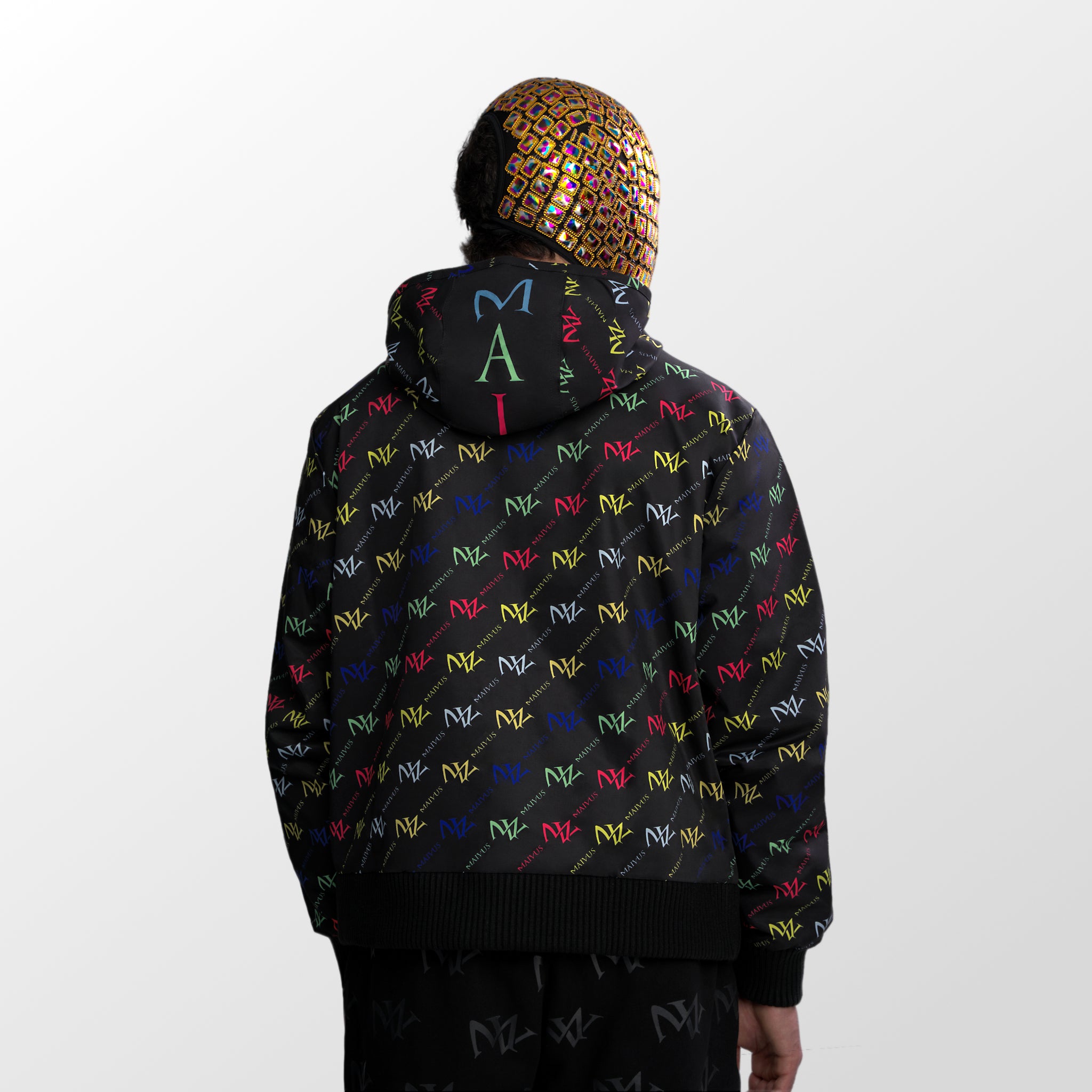Model wearing the luxury multicolored jacket with 'MV' branding from 'MAIVUS' against a white studio backdrop