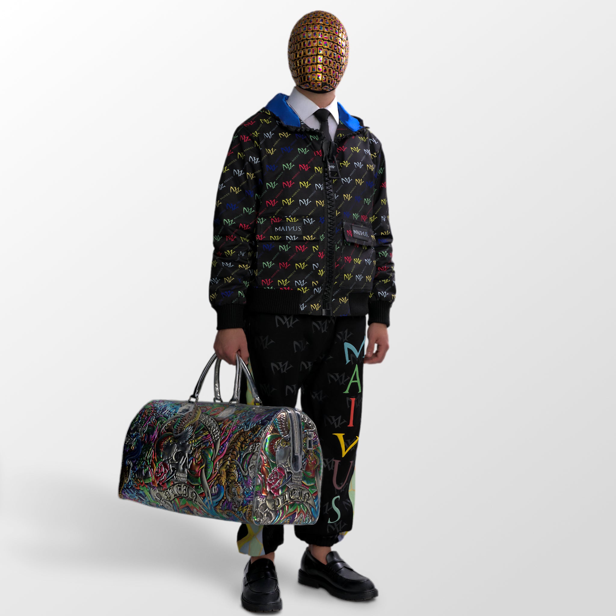 Model wearing the luxury multicolored jacket and joggers with 'MV' branding and geometric shapes from 'MAIVUS' against a white studio backdrop