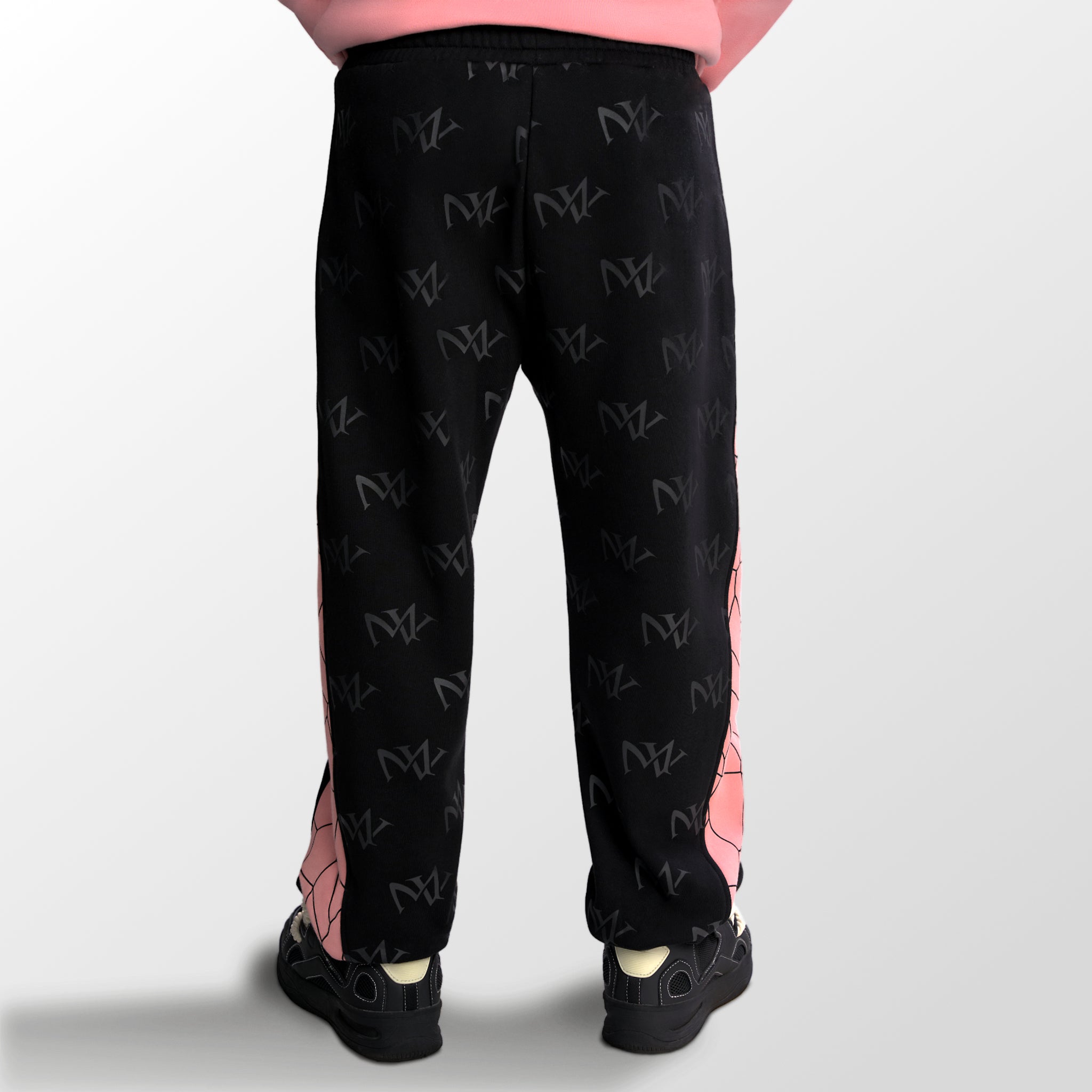 Model wearing the luxury black and pink joggers with 'MV' branding and geometric shapes from 'MAIVUS' against a white studio backdrop