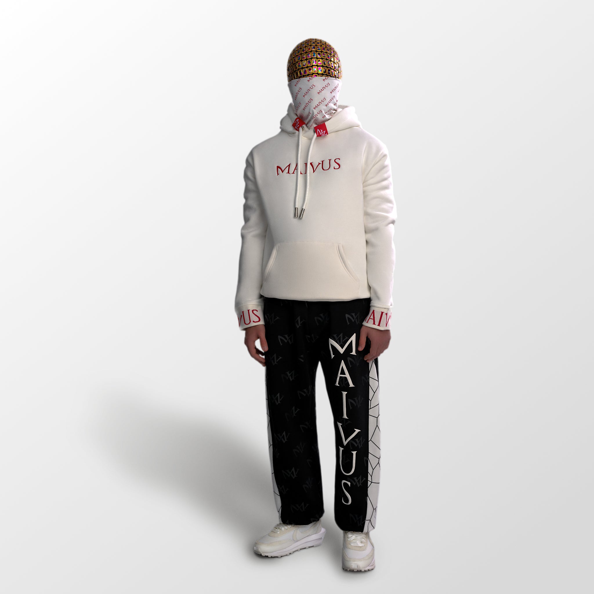 Model wearing a luxury white and red hoodie and black and white joggers. 'MV' branding on joggers with geometric shapes and red embroidery with branded snood on hoodie from 'MAIVUS' against a white studio backdrop