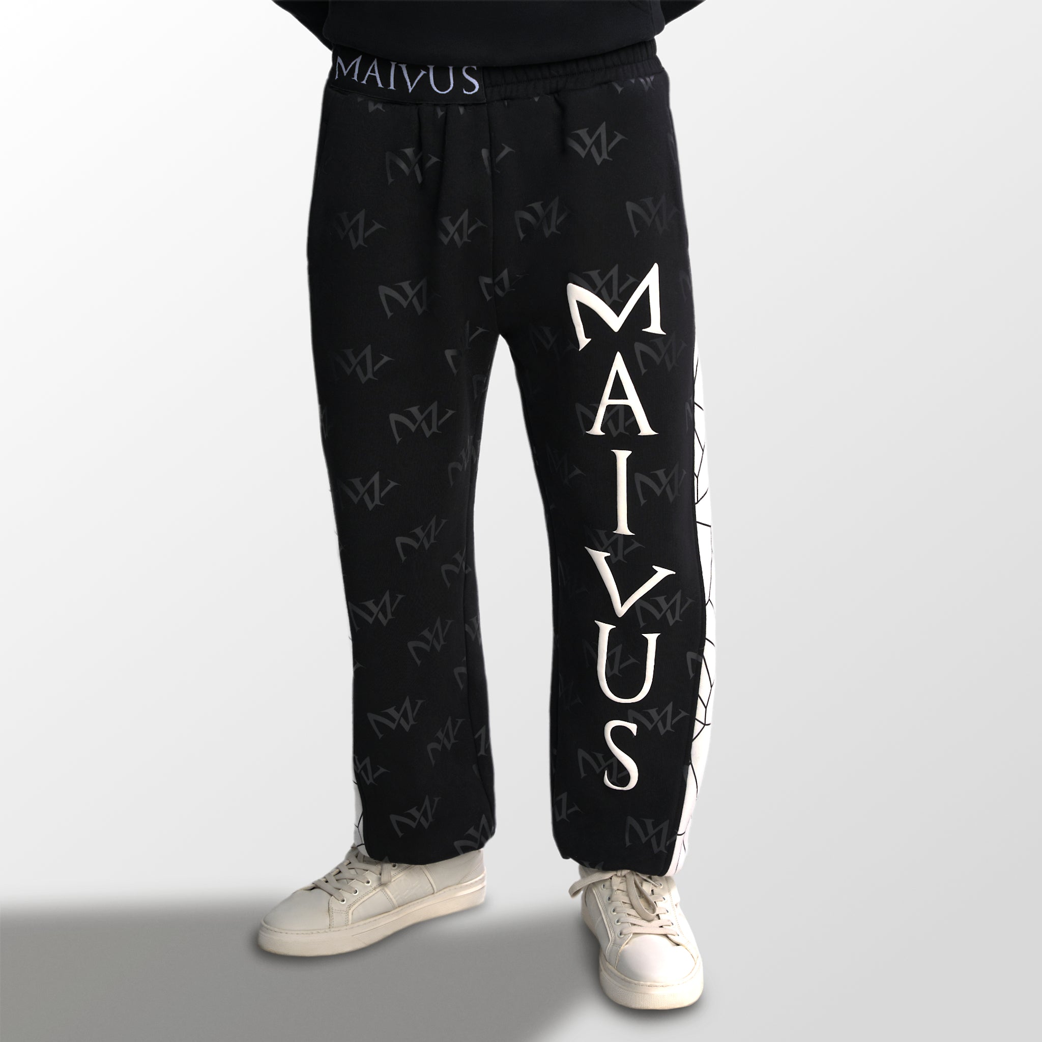 Model wearing the luxury white and black joggers with 'MV' branding and geometric shapes from 'MAIVUS' against a white studio backdrop