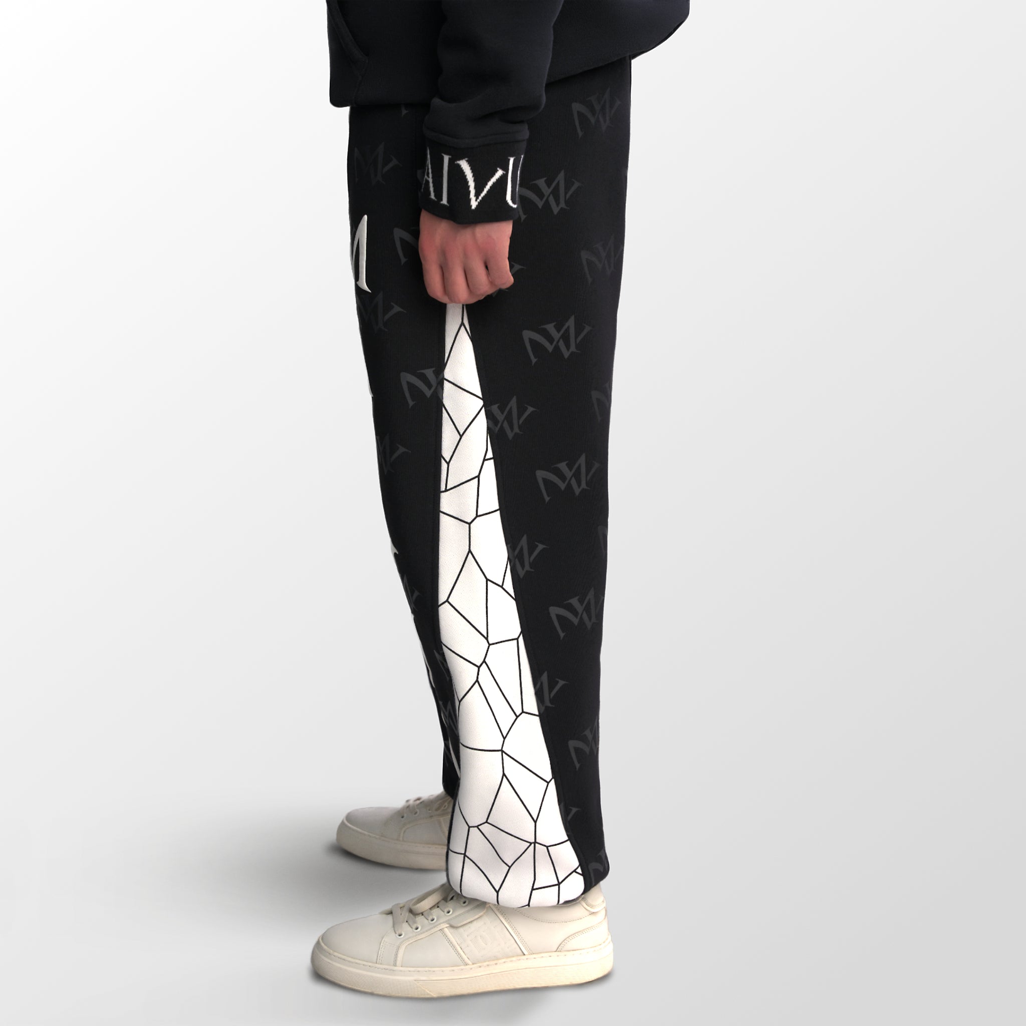 Model wearing the luxury white and black joggers with 'MV' branding and geometric shapes from 'MAIVUS' against a white studio backdrop